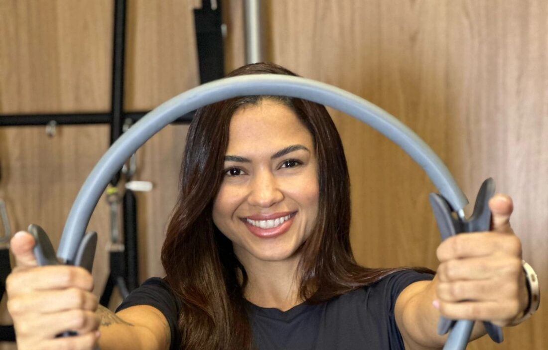 Carla sorrindo, segurando um anel de pilates